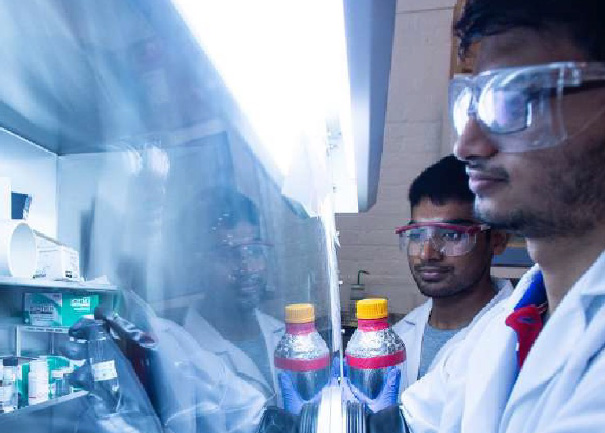 Two researchers wearing safety goggles review research