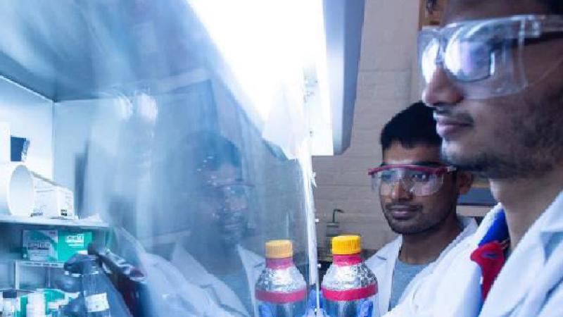 Two researchers wearing safety goggles review research